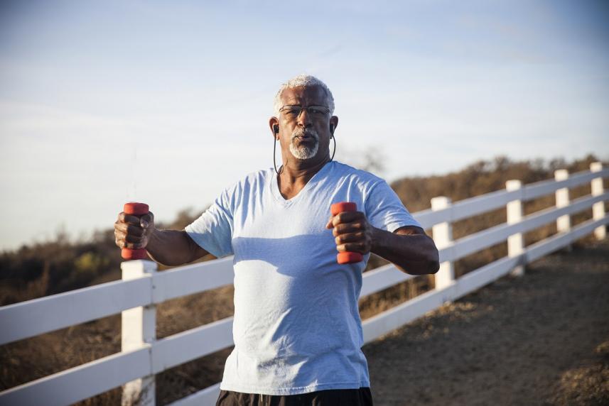 Older man exercising outside with dumbbells