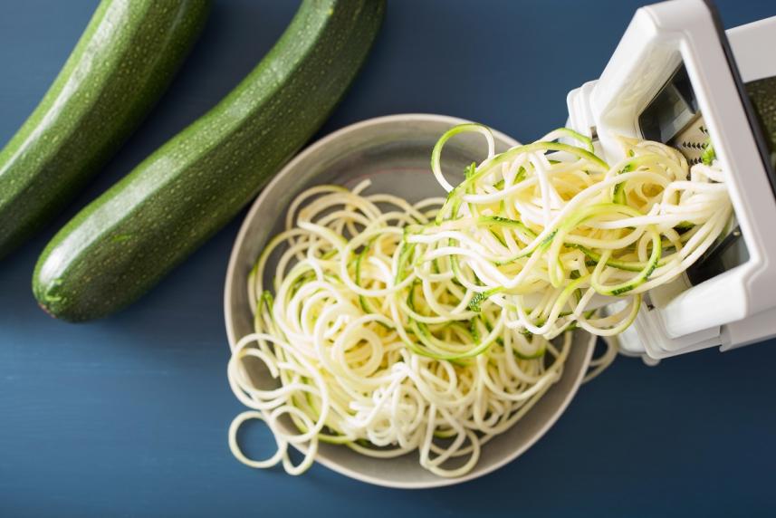 Zucchini being formed into pasta noodle-like strands (zoodles) with a spiralizer