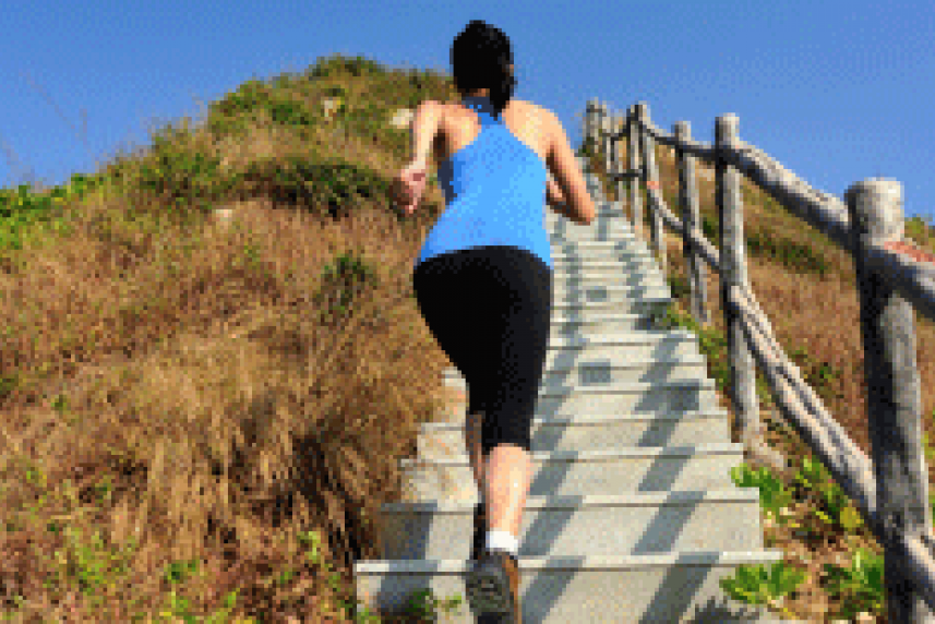 Photo: Fit woman running up a long set of outdoor stairs on a mountain