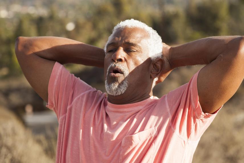 Man holding the back of his head, taking a deep breath outside