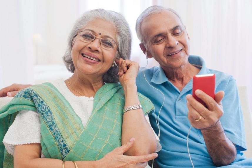 Photo: Mature couple wearing headphones and listening to something on their smartphone.