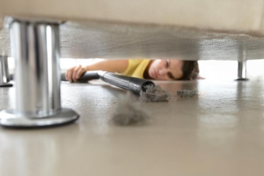Woman vacuuming under couch