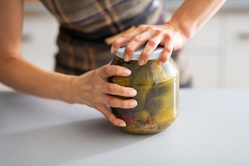 Woman trying to open a jar of pickle 
