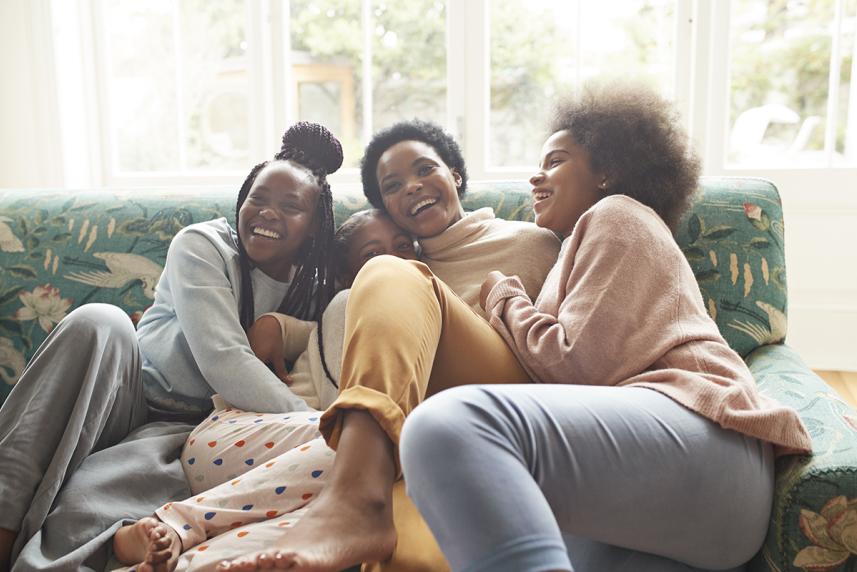A mother and her three daughters share a laugh on the couch. 