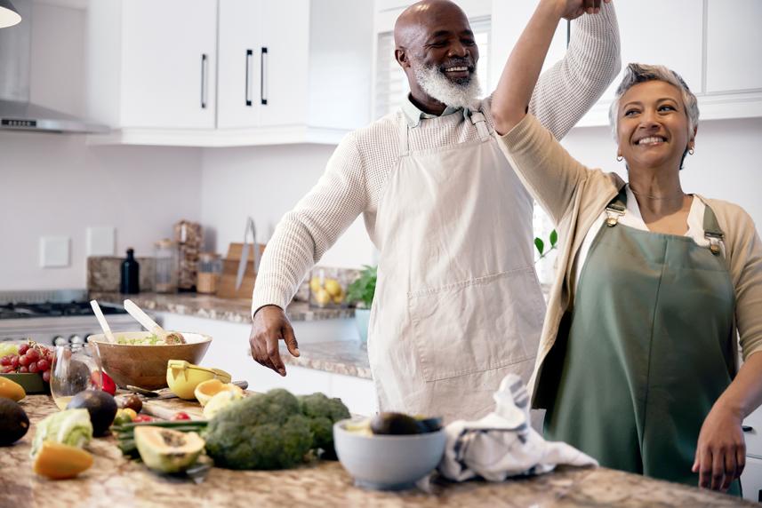 Mature couple dancing and cooking in kitchen