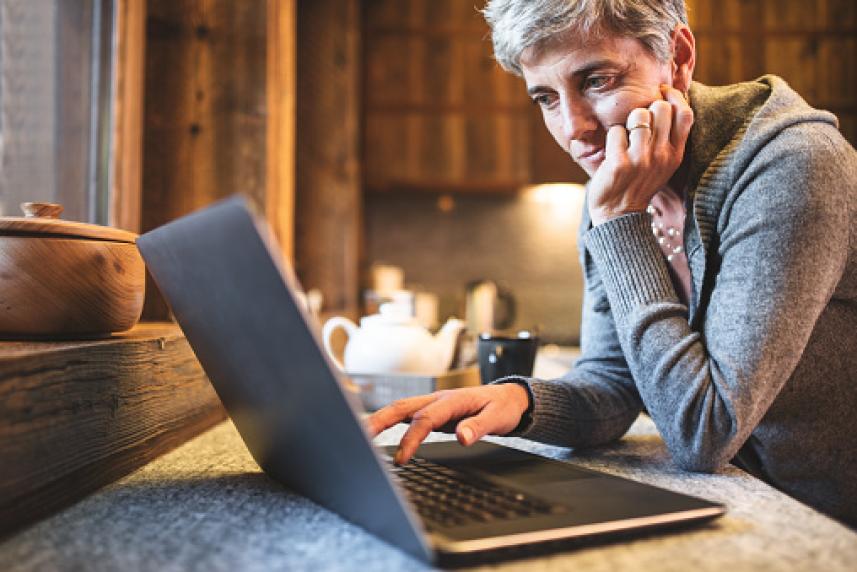 Photo: Woman at kitchen counter working on a laptop computer