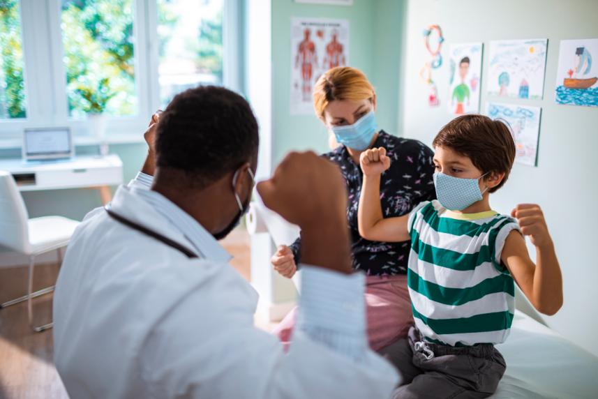 A young boy flexing for fun to a doctor at a doctor's appointment