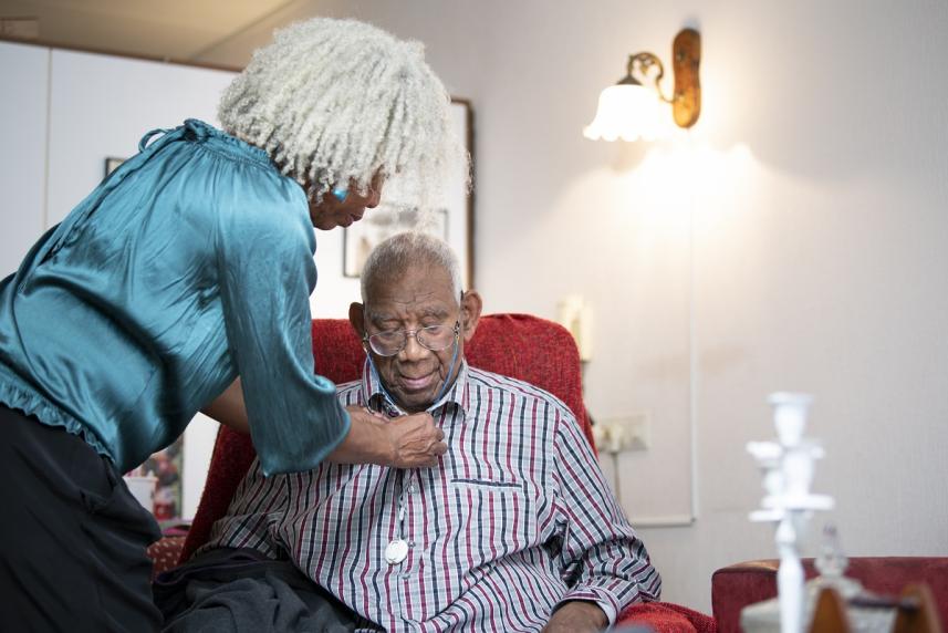 Older woman helping husband with his shirt