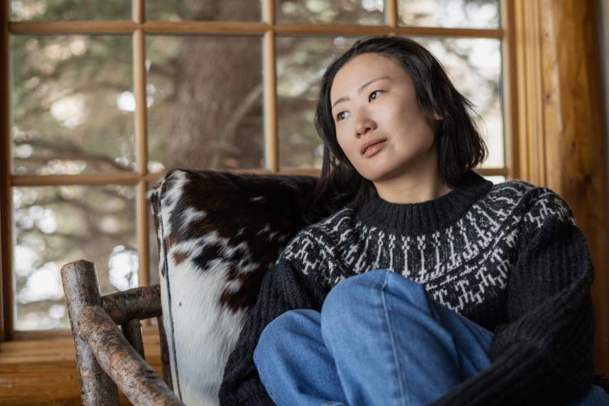 Woman sitting on a seat in front of a window, looking to the side