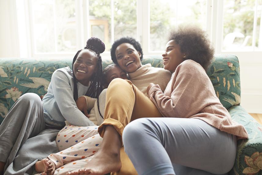 A mother and her three daughters share a laugh on the couch. 