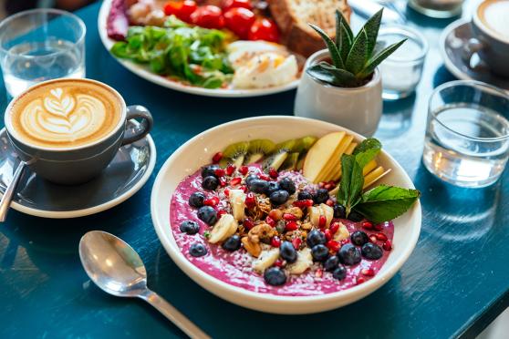 Health breakfast of blueberry, kiwi, banana, apple, nuts, yogurt, spinach, tomato, coffee, eggs, toast 