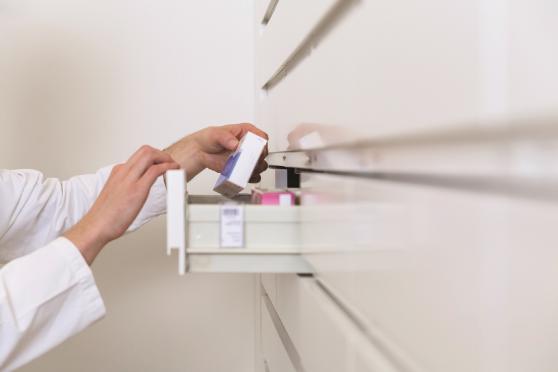 Doctor grabbing medicine box from cabinet