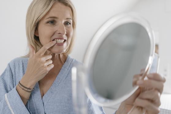 Woman checking teeth with mirror
