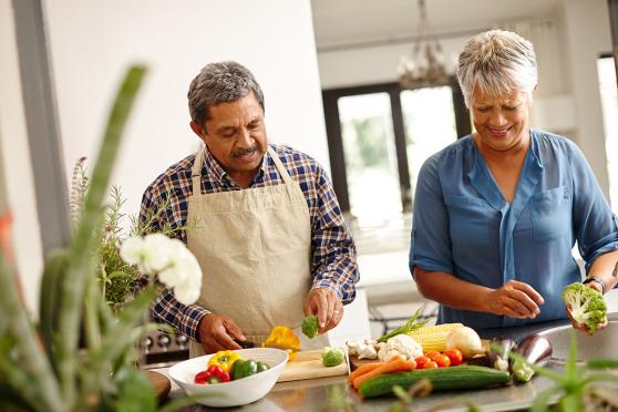 A couple in the kitchen cutting up vegetables