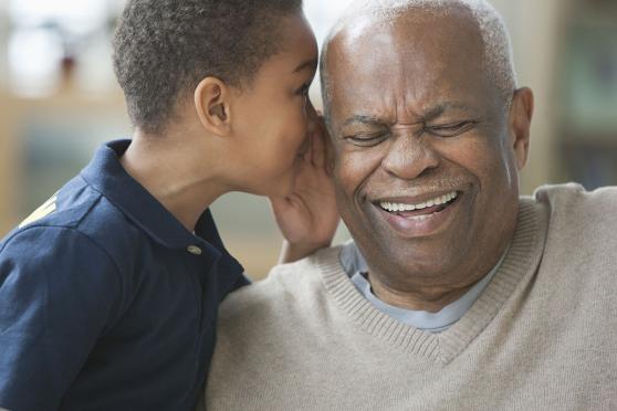 Young boy whispers in older man's ear