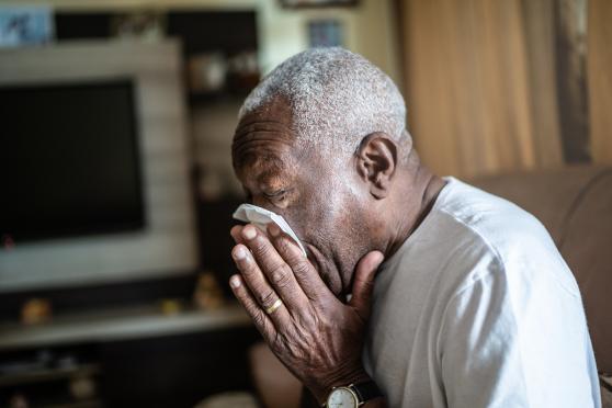 Man blowing his nose into a tissue