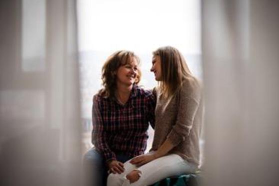 Photo: Woman and her daughter smiling and sitting by a window