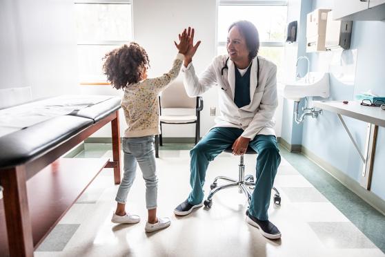 A child and a doctor high-fiving in the doctors office
