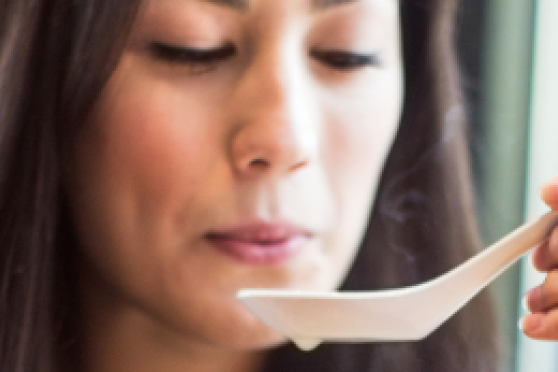 A woman prepares to take a sip of soup from a soup spoon