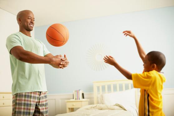 Father and son playing around with a ball indoors