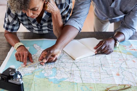 Photo: Woman and man looking at a road map and planning a trip.