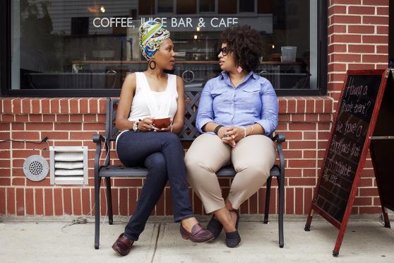 Two women sit and chat on a bench outside a local cafe.